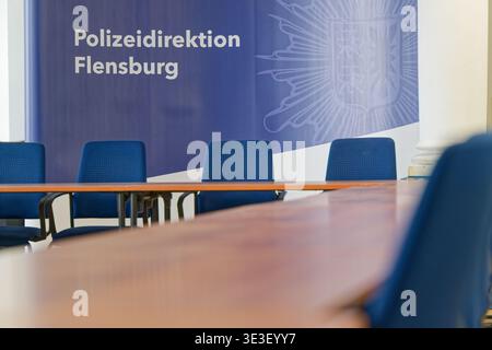 Une salle de conférence vide avec des chaises bleues et une table en bois avec une bannière du service de police en arrière-plan, créant une atmosphère professionnelle Banque D'Images