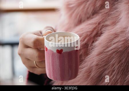 Personne tient une tasse avec des coeurs dans un cadre confortable Banque D'Images