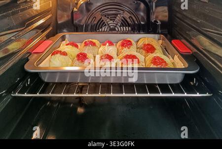 Rouleaux de chou surmontés de sauce tomate cuisson au four, processus de cuisson de repas maison montrant un plat traditionnel préparé à l'intérieur de l'appareil de cuisine. Banque D'Images