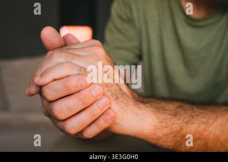 Gros plan des mains rugueuses et veinées d'un homme d'âge moyen serrées ensemble dans un geste de prière, de plaidoyer ou de réflexion profonde. Mise au point sélective. Banque D'Images