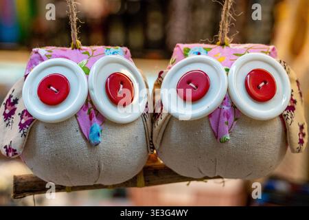 Jolies décorations de hibou artisanales accrochées à une branche. Les yeux boutons blancs avec des centres rouges les rendent charmants. Le tissu fleuri rose ajoute une touche ludique. Chacun Banque D'Images