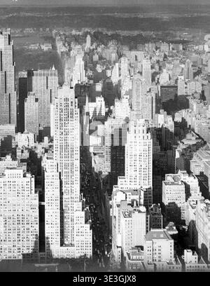 Cette photographie aérienne en noir et blanc saisissante capture un paysage urbain dense de gratte-ciel de New York, probablement des années 1940 Les longues ombres projetées par les grands bâtiments sur les avenues en contrebas soulignent la grandeur architecturale de la ville et l'activité animée au niveau de la rue. Photographiée par Angelo Rizzuto, cette image offre un aperçu historique de l'emblématique skyline de Manhattan. Banque D'Images