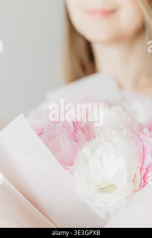 Jeune femme tenant un bouquet de pivoines blanches roses Banque D'Images