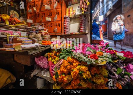 Un vendeur de rue expose des soucis vibrants et des fleurs de lotus à vendre dans une ruelle étroite de la vieille ville de Varanasi. Banque D'Images