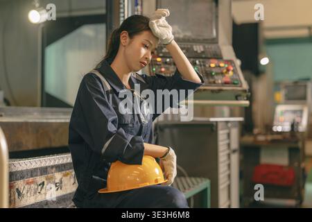 Jeune femme asiatique travailleur dur travail dans l'industrie lourde, travail d'ingénieur femme fatigue épuisée expression épuisée repos dans l'usine d'usine de métal Banque D'Images