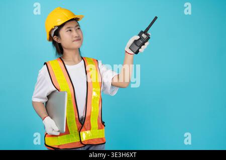Ingénieur portrait femme asiatique adolescent avec gilet réfléchissant de sécurité modèle isolé utilisant radio pointant à l'espace de copie Banque D'Images