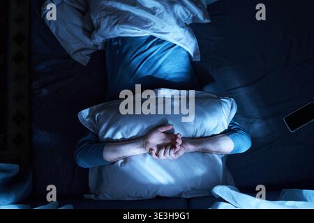 Homme adulte allongé éveillé dans le lit souffrant d'insomnie Banque D'Images