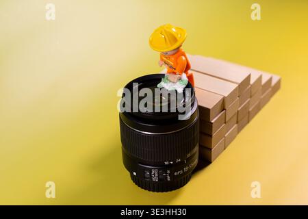 Image conceptuelle créative de petites figurines jouet effectuant le nettoyage et l'entretien d'un objectif d'appareil photo. Banque D'Images