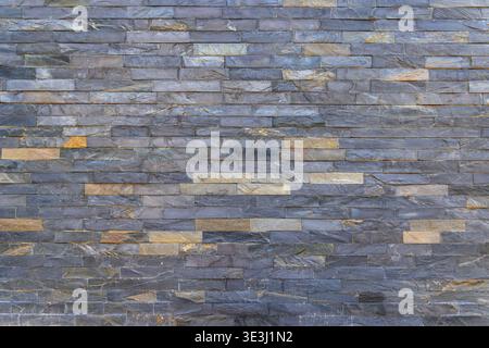 Texture de mur en pierre empilée bleu gris. Vue plein cadre d'un mur en pierre empilée gris bleu avec des morceaux d'ardoise horizontaux, variation naturelle et moderne Banque D'Images