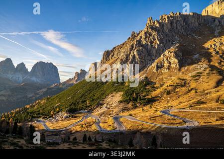 Vue spectaculaire sur Gardena Pass route sinueuse dans les Dolomites. La lumière chaude du coucher de soleil illumine les murs du groupe Sella, avec le profil Sassolungo dans le di Banque D'Images