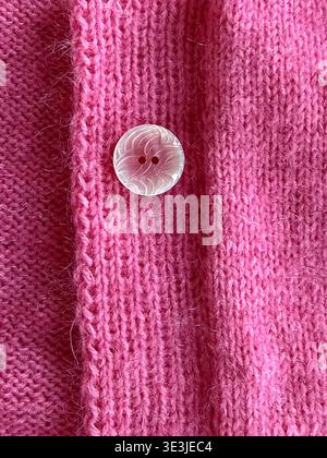 Gros plan de cardigan tricoté rose avec boutons décoratifs, texture textile et détail tricot fait main, mode lente et concept de vêtements durables Banque D'Images