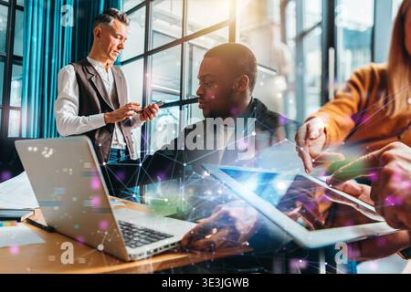 Groupe de personnes travaillant ensemble dans un bureau moderne pendant la journée sur divers appareils numériques Banque D'Images
