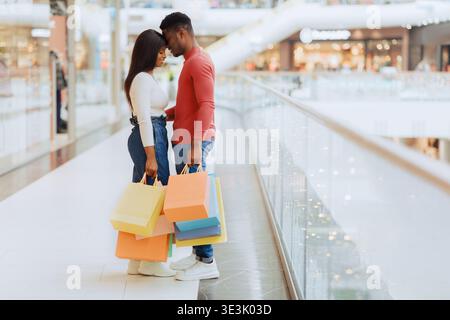 Couple aime faire du shopping ensemble au centre commercial avec des sacs colorés dans leurs mains Banque D'Images
