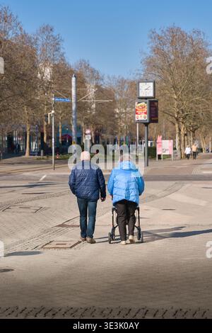 Un couple de retraités âgés, l'un utilisant un déambulateur, dehors pour une promenade dans la ville de Magdebourg, en Allemagne Banque D'Images