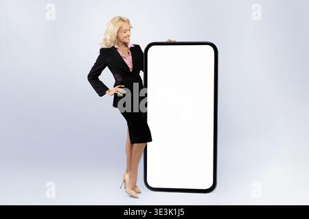 Femme d'affaires se tient près d'un grand écran vierge pour la présentation dans un cadre de studio Banque D'Images