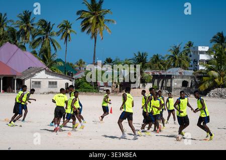 PAJE, ZANZIBAR - 18 OCTOBRE 2025 : L'équipe de football Paje Star en maillots jaune vif s'entraîne sur une plage de sable blanc dans un village de Zanzibar sous un tropi Banque D'Images