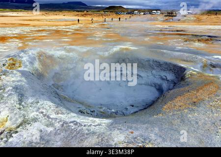 La vapeur s'élève du sol aux sources chaudes de Hverir en Islande. Les visiteurs explorent la région, observant les caractéristiques géothermiques et la boue bouillante. Banque D'Images