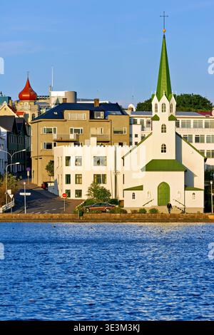 L'église libre luthérienne se trouve près du lac Tjornin à Reykjavik, avec des bâtiments et des rues montrant l'activité dans la région pendant la journée. Banque D'Images