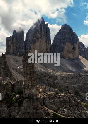Vue aérienne des majestueux sommets de Tre Cime di Lavaredo perçant le ciel, leurs surfaces accidentées contrastant avec des nuages doux et éthérés, Tre cime Lavare Banque D'Images