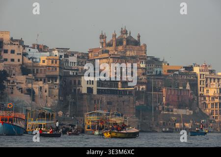 Vue des ghats s'élèvent au-dessus du fleuve Gange, où les bateaux colorés bob doucement, reflétant la lumière chaude du crépuscule, Varanasi, Uttar Pradesh, Inde. Banque D'Images