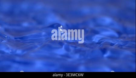 L'eau coule doucement en bleu clair, créant des vagues et des ondulations dans un cadre calme sous une lumière vive pendant la mi-journée Banque D'Images