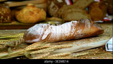 Pain fraîchement cuit sur une planche de bois avec du blé et d'autres types de pain dans un cadre de boulangerie Banque D'Images