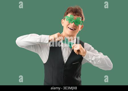 Serveur rousse dans des lunettes en forme de trèfle sur fond vert. Célébration de la fête de Patrick Banque D'Images