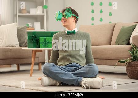 Rougeâtre jeune homme dans des lunettes en forme de trèfle à la maison le jour de Patrick Banque D'Images