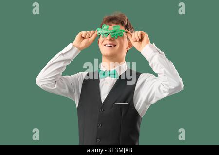 Serveur rousse dans des lunettes en forme de trèfle sur fond vert. Célébration de la fête de Patrick Banque D'Images
