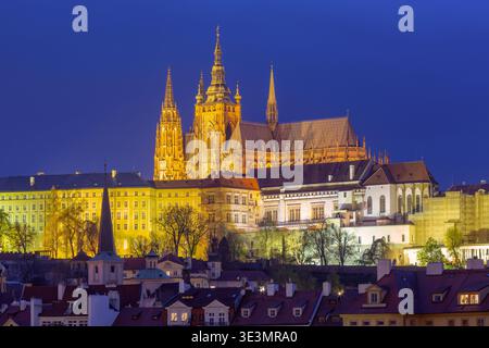 Le pont Charles et le château de Prague sont illuminés au-dessus de la rivière Vltava à l'aube à Prague, en République tchèque, sous des nuages bleus spectaculaires. Banque D'Images