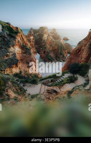 Vue aérienne des falaises escarpées embrassent une plage cachée, où le sable doré rencontre la mer turquoise, Lagos, Portugal. Banque D'Images