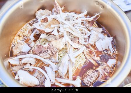 Quatre photos montrent le processus de cuisson étape par étape du ramyeon de champignon de pin coréen dans un pot doré traditionnel, mettant en valeur un délice d'automne aromatique Banque D'Images