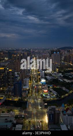 Vue aérienne d'une longue route coupant à travers un paysage urbain, des lumières floues en stries d'or sous un ciel lourd de nuages d'orage, Kaohsiung, Kaohsiung Banque D'Images
