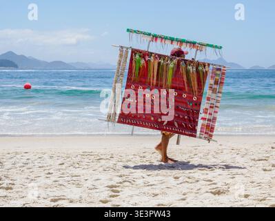 Un marchand vendant ses marchandises sur un grand panneau d'affichage sur la plage de Copacabana à Rio de Janeiro Brésil Banque D'Images