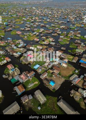 Vue aérienne de maisons sur pilotis s'élèvent des eaux, une tapisserie vibrante de toits et de reflets, reflétant le ciel au-dessus, Ganvié, Bénin. Banque D'Images