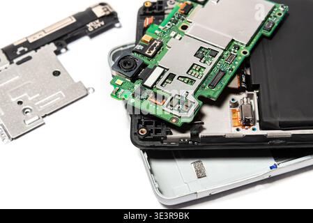 Un smartphone en cours de réparation avec sa coque arrière retirée et les composants intérieurs visibles sur une surface de travail. Des outils sont utilisés pour la réparation. Banque D'Images