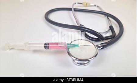 Seringue contenant un liquide rose placé sur un stéthoscope médical représentant les soins de santé Banque D'Images