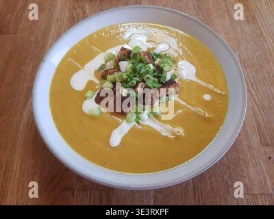 Soupe de panais et de carottes. Arrosé de yaourt. Servi avec croûtons, oignon de printemps et persil Banque D'Images