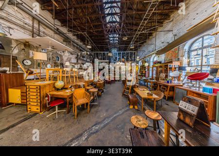 Un magasin d'antiquités installé dans un entrepôt industriel reconverti avec un toit en verre et des poutres de toit en fonte : meubles, lampes, horloges et petits objets de différentes décennies du XXe siècle, exposés côte à côte. Leipzig, Saxe, Allemagne Banque D'Images