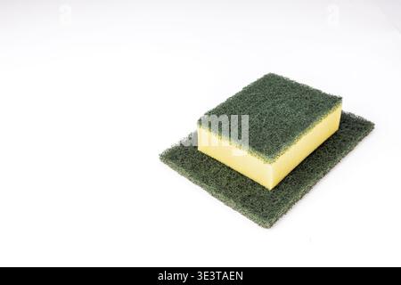 Une toute nouvelle éponge de cuisine double couche avec une base en mousse jaune et une surface de récurage abrasive verte repose sur un plus grand tampon à récurer vert plat, bo Banque D'Images