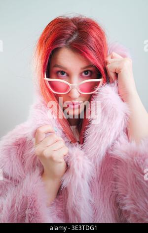 Belle jeune femme aux cheveux roux et manteau de fourrure rose, portrait de studio Banque D'Images