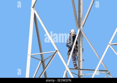 Technicien en hauteur / grimpeur de tour / technicien d'accès de corde effectuant des travaux d'entretien sur le pylône d'électricité haute tension / tour de transmission Banque D'Images