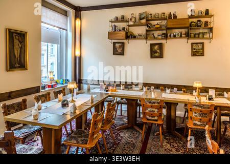 La salle à manger du restaurant Kollektiv de Leipzig est décorée dans un style traditionnel, avec des chaises et des tables en bois, des chemins de table, des tasses à bière et de la porcelaine sur les étagères murales, ainsi que des peintures de paysage sur les murs. Leipzig, Saxe, Allemagne Banque D'Images