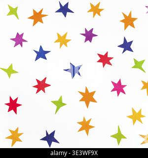 Vue de dessus de diverses étoiles sculptées dans du papier coloré sur fond carré blanc Banque D'Images