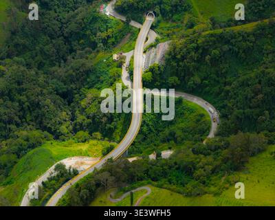 Une vue aérienne de l'autoroute la linea en Colombie met en valeur la route sinueuse traversant des montagnes verdoyantes et des forêts denses, illustrant ainsi le stunnin Banque D'Images