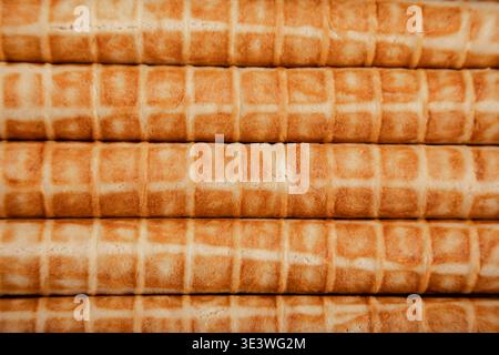 Gros plan de tubes gaufrés cuits disposés en pile nette. Chaque tube présente une texture croustillante, brun doré, soulignant le délicieux treillis Banque D'Images