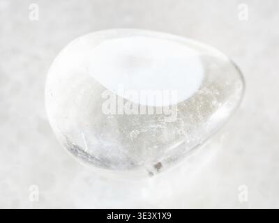 Plan macro d'un échantillon de roche naturelle de pierre précieuse en cristal de roche poli sur fond de marbre blanc Banque D'Images