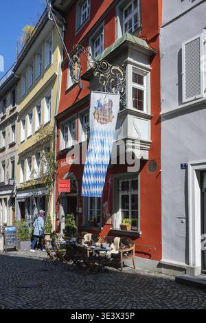 Pittoresque ruelle de la vieille ville avec des restaurants en plein air au-dessus d'un drapeau de l'État bavarois dans la vieille ville de Lindau, Bavière, Allemagne Banque D'Images