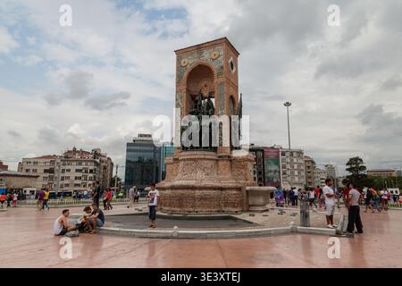 Les touristes et les habitants moulent autour de l'emblématique Monument de la République sur la place Taksim animée sous un ciel nuageux spectaculaire dans le centre d'Istanbul, en Turquie Banque D'Images