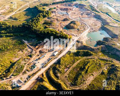 Vue aérienne d'une carrière active à ciel ouvert avec de multiples fosses excavées et piscines d'eau turquoise. Un chemin de terre serpente à travers le paysage industriel, Banque D'Images